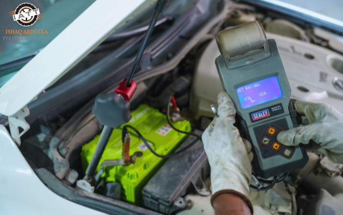 IATT technician testing car battery health during winter car care service in Dubai using a digital battery analyzer
